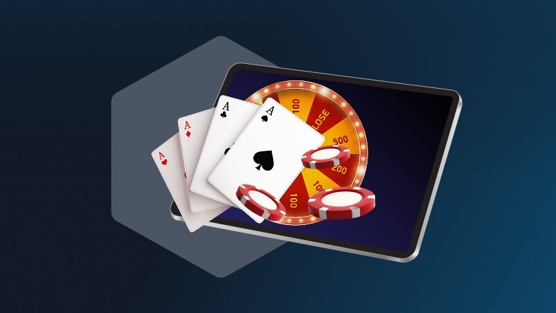 Digital illustration of a tablet displaying a casino roulette wheel, with playing cards and poker chips in the foreground representing online gambling